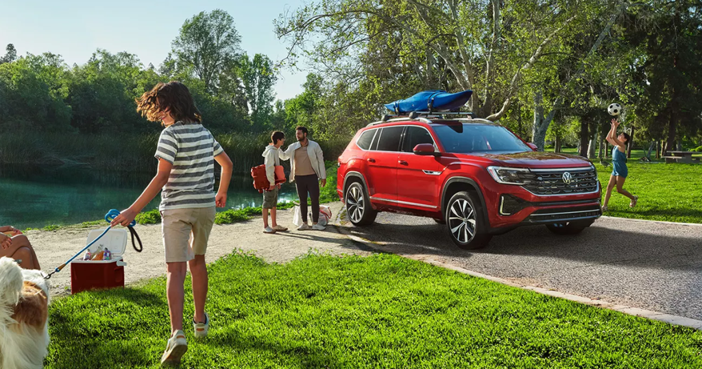An active family hanging out around their 2024 Volkswagen Atlas in aurora red metallic parked in the driveway