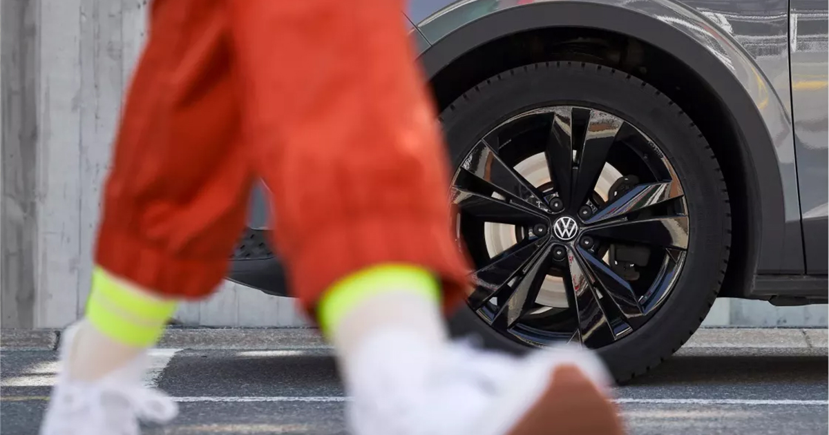 Close-up of a service technician's feet walking away from a Volkswagen vehicle in the service center.