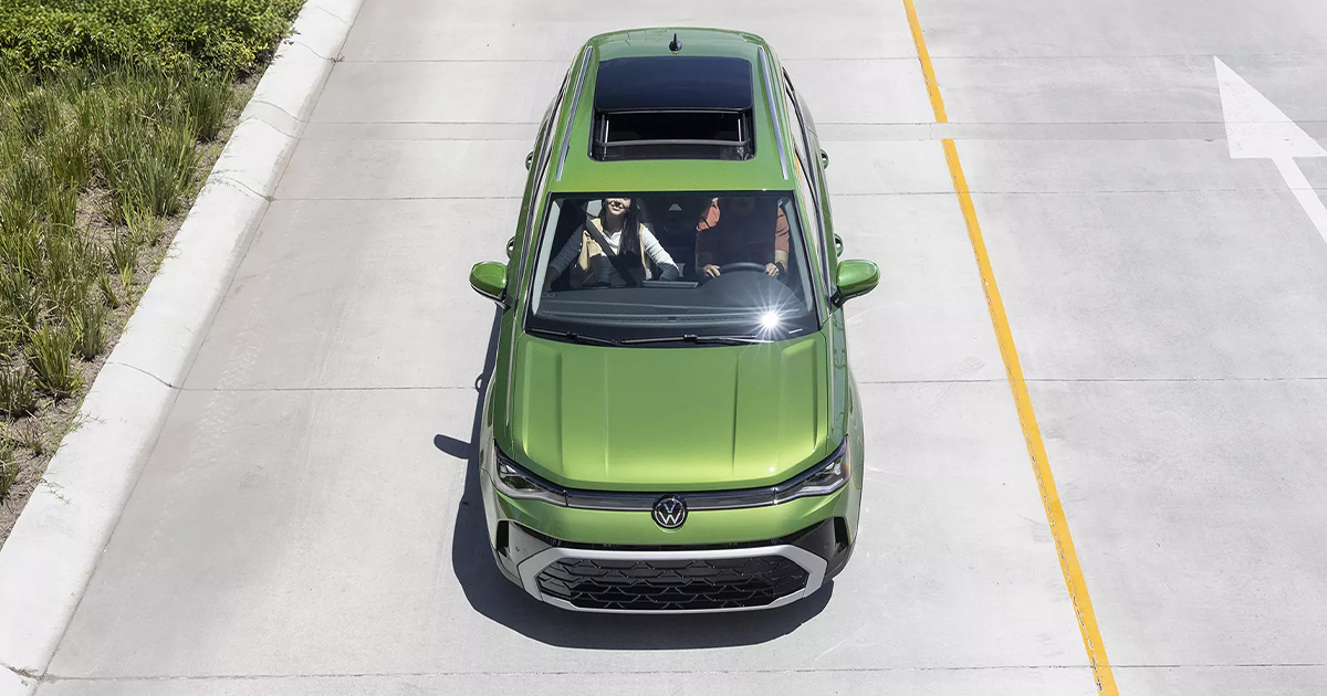 Overhead view of a green Volkswagen Taos being driven by a couple during the day.