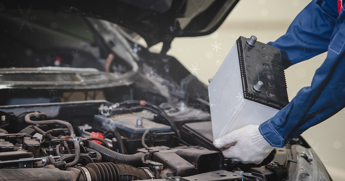 A close-up of a service technician's hands as they place a battery in the vehicle's engine