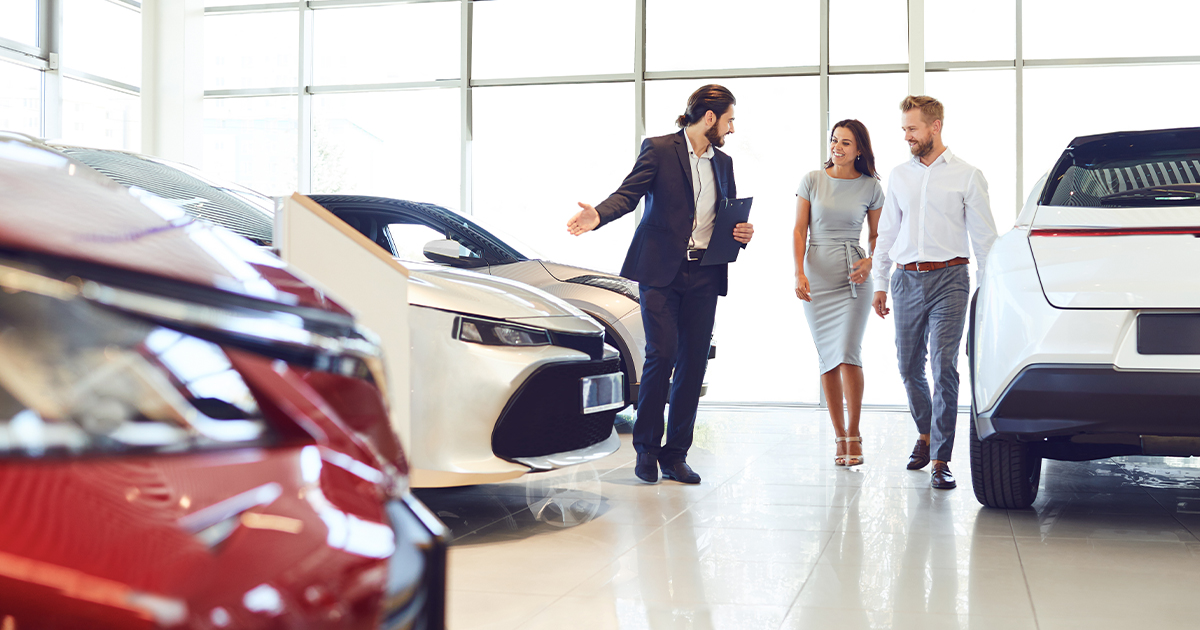 A car salesperson showing a family the variety of vehicles available in the dealership showroom.