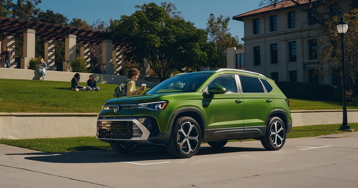A bright green Volkswagen Taos subcompact SUV parked outdoors near a campus building.